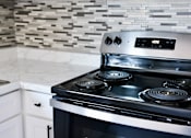 Thumbnail 3 of 30 - A modern stove top with a digital display is in a kitchen with a marble counter.