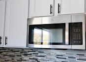 Thumbnail 4 of 30 - A stainless steel microwave oven is installed above a tiled backsplash in a kitchen.