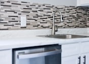 Thumbnail 1 of 30 - A modern kitchen with a marble countertop and a stainless steel sink.