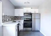 Thumbnail 7 of 30 - A modern kitchen with stainless steel appliances and white cabinets.
