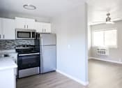 Thumbnail 5 of 30 - A kitchen with a stove top oven, microwave, and refrigerator.