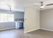 Thumbnail 6 of 30 - A room with a ceiling fan and a window overlooking a kitchen.