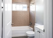 Thumbnail 8 of 30 - A bathroom with a toilet, sink, and bathtub.