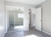 Thumbnail 25 of 30 - A room with a white door and a mirror on the wall.