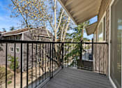 Thumbnail 12 of 18 - A balcony with a black railing and a view of a house and trees.
