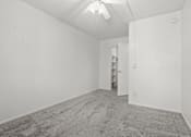 Thumbnail 5 of 18 - A room with a carpeted floor and a ceiling fan.