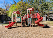 Thumbnail 13 of 18 - A playground with a red slide and a green and red climbing structure.