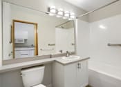Thumbnail 24 of 32 - A white bathroom with a toilet, sink, and mirror.