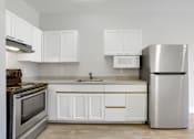 Thumbnail 14 of 32 - A modern kitchen with white cabinets and stainless steel appliances.