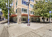 Thumbnail 5 of 32 - A building with a red awning is surrounded by trees and street lamps.