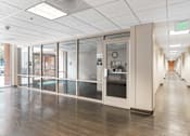 Thumbnail 6 of 12 - A long hallway with a glass door and a green exit sign at Pin Yuen, Sacramento, CA