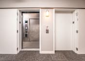 Thumbnail 26 of 32 - A white door with a silver elevator in the background.
