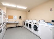 Thumbnail 27 of 32 - A laundry room with washing machines and a sign on the wall.