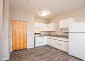 Thumbnail 16 of 32 - A kitchen with white appliances and wooden floors.