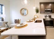 Thumbnail 7 of 28 - a kitchen and living room with a white counter top and a sink