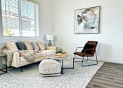 Thumbnail 25 of 31 - A living room with a beige couch, a chair, a small table, and a painting on the wall at Zora Encanto, Phoenix, 85035