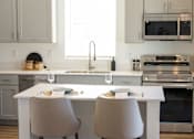 Thumbnail 22 of 31 - A kitchen with a white countertop and two chairs at Zora Encanto, Phoenix