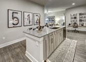 Thumbnail 25 of 40 - A kitchen with a white island and a rug on the floor at Arise Riverside Apartments, Austin, 78741