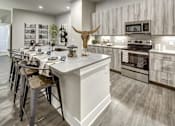 Thumbnail 24 of 40 - A modern kitchen with a white island and a cow skull as a decoration at Arise Riverside Apartments, Texas