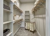 Thumbnail 30 of 40 - A walk-in closet with white shelves and hangers at Arise Riverside Apartments, Austin