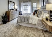 Thumbnail 29 of 40 - A bedroom with a large bed, a dresser, and a ceiling fan at Arise Riverside Apartments, Austin