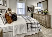 Thumbnail 32 of 40 - A bedroom with a bed, dresser, and mirror at Arise Riverside Apartments, Texas