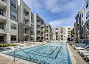 Thumbnail 2 of 40 - A large swimming pool in the middle of a courtyard surrounded by apartment buildings at Arise Riverside Apartments, Austin, TX