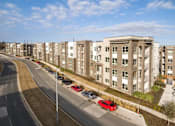Thumbnail 40 of 40 - A row of apartment buildings with cars parked in front at Arise Riverside Apartments, Austin, Texas