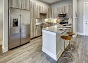 Thumbnail 27 of 40 - A modern kitchen with a white island and stainless steel appliances at Arise Riverside Apartments, Texas 78741