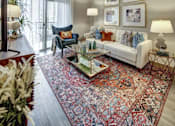 Thumbnail 21 of 40 - A living room with a white couch, a blue chair, and a large rug at Arise Riverside Apartments, Austin, TX, 78741