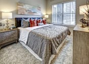 Thumbnail 34 of 40 - A bedroom with a large bed and a painting on the wall at Arise Riverside Apartments, Austin, Texas