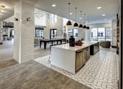 Thumbnail 12 of 40 - A modern kitchen with a white island and a dining area with a table and chairs at Arise Riverside Apartments, Texas 78741