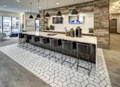 Thumbnail 6 of 40 - A modern kitchen with a long island and bar stools at Arise Riverside Apartments, Austin, TX