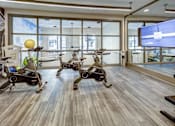 Thumbnail 20 of 40 - A room with exercise bikes and a TV screen at Arise Riverside Apartments, Texas