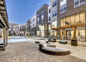 Thumbnail 15 of 40 - A modern outdoor pool area with a wooden deck and lounge chairs at Arise Riverside Apartments, Texas