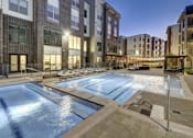 Thumbnail 1 of 40 - A swimming pool in front of apartment buildings at dusk at Arise Riverside Apartments, Austin