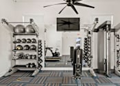 Thumbnail 16 of 31 - a home gym with weights machines and a ceiling fan at Zora Encanto, Phoenix, AZ 85035