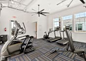 Thumbnail 18 of 31 - a gym with cardio machines and a ceiling fan at Zora Encanto, Phoenix, AZ