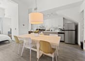 Thumbnail 2 of 25 - a dining room with a wooden table and chairs and a kitchen with stainless steel appliances