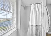 Thumbnail 9 of 35 - a bathroom with a shower and white curtains and a window with white blinds