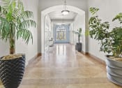 Thumbnail 19 of 35 - a hallway with potted plants and white walls and a blue door