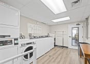 Thumbnail 11 of 35 - a laundry room with a washer and dryer and a table and a door