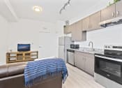 Thumbnail 1 of 24 - a living room with a leather couch and a kitchen with stainless steel appliances