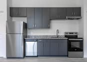 Thumbnail 21 of 24 - A modern kitchen with a stainless steel refrigerator, a dishwasher, a sink, and a stove.