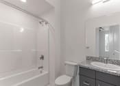 Thumbnail 18 of 24 - A white bathroom with a toilet, sink, and bathtub.