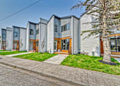 Thumbnail 1 of 73 - A row of modern houses with grey siding and wooden doors.