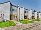 Thumbnail 2 of 73 - A row of modern houses with grey siding and wooden doors.
