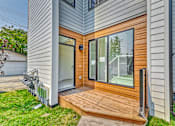Thumbnail 3 of 73 - A modern house with a wooden deck and sliding glass doors.