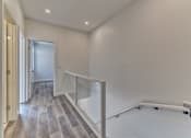 Thumbnail 24 of 73 - A hallway with a wooden floor and white walls.