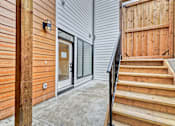 Thumbnail 7 of 73 - A wooden staircase leads to a glass door entrance.